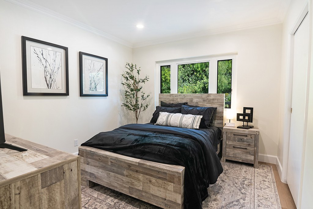 A bedroom at the Winnetka home with a queen bed, reclaimed-wood furniture and a window onto the garden