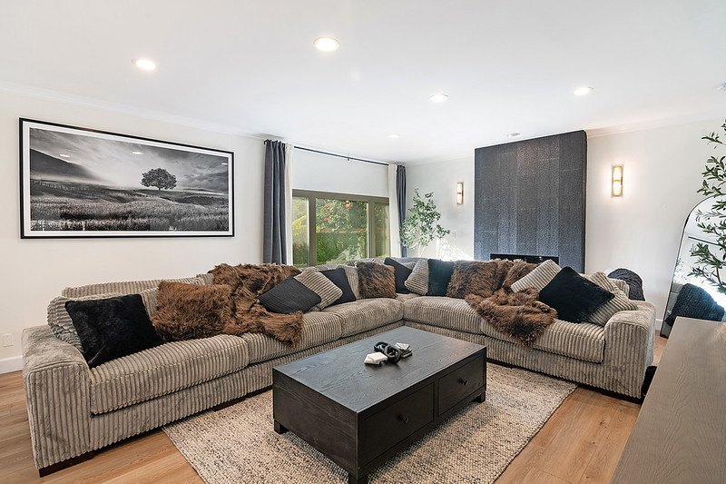 A family room with a large corduroy sectional, soft throws and a dark tiled fireplace