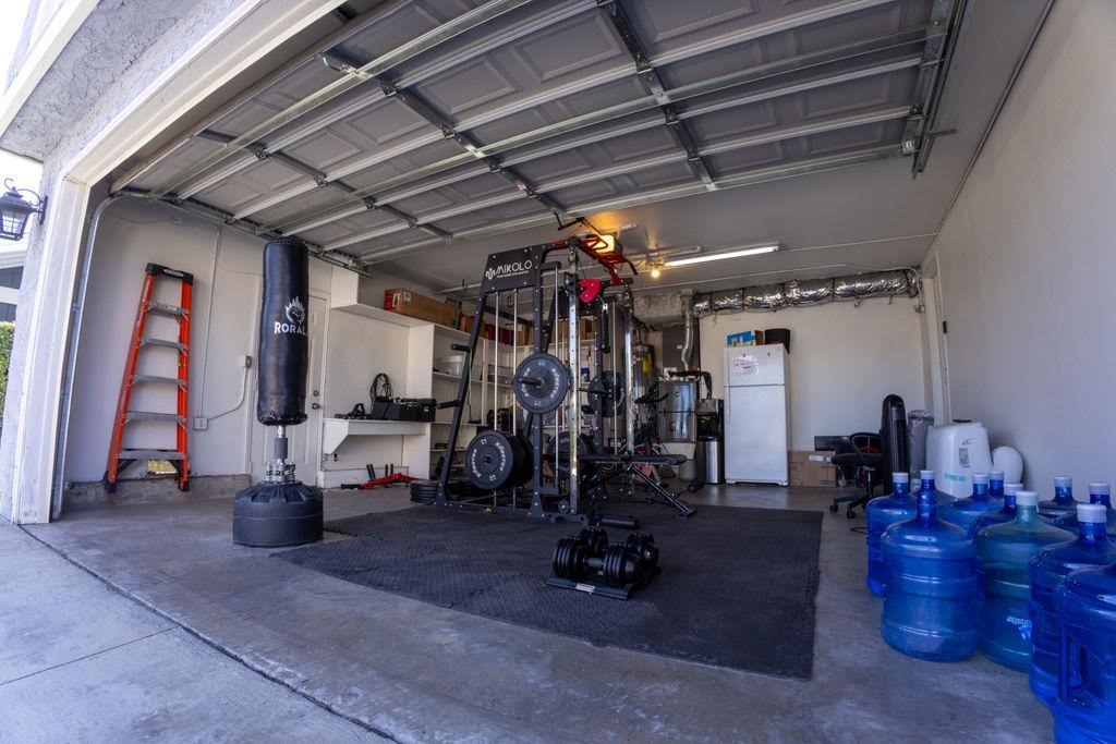 A home gym in the Home B garage, with a squat rack, free weights, a punching bag and floor mats