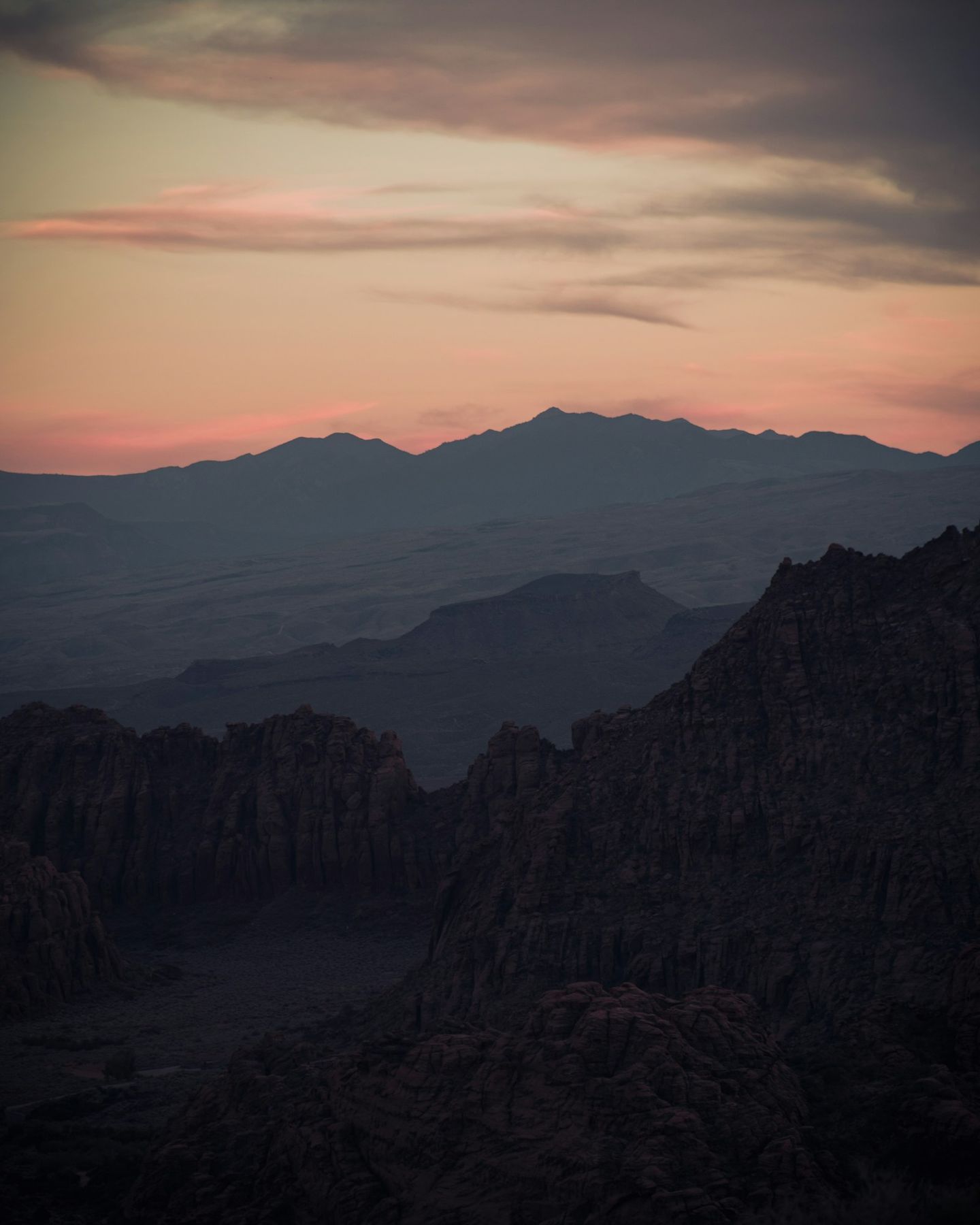 Layered mountain ridges under a pink and blue sky at sunset